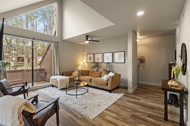 living room with recessed lighting, visible vents, a towering ceiling, wood finished floors, and baseboards