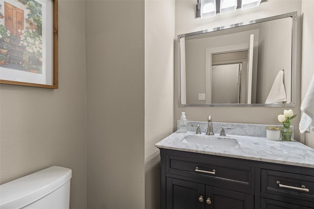 bathroom featuring a textured wall, vanity, and toilet