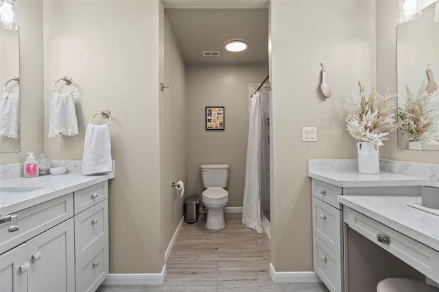 bathroom with baseboards, visible vents, toilet, wood finished floors, and vanity