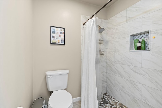 bathroom featuring baseboards, tiled shower, and toilet