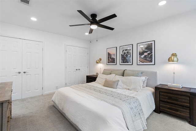 bedroom with recessed lighting, multiple closets, and light colored carpet