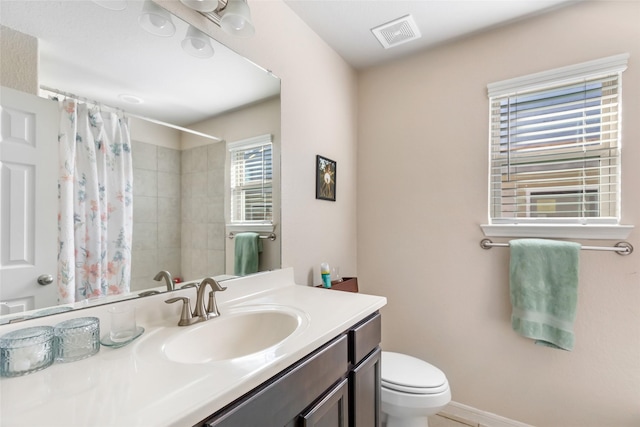 bathroom with visible vents, toilet, vanity, a shower with curtain, and baseboards