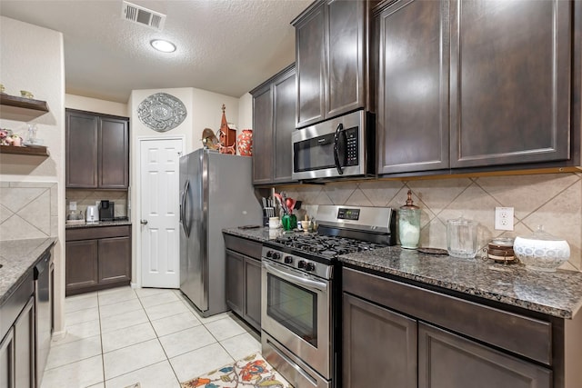 kitchen with open shelves, stainless steel appliances, visible vents, dark brown cabinetry, and dark stone countertops