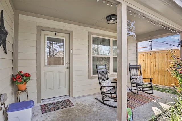 entrance to property featuring covered porch and fence