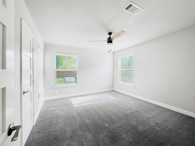 carpeted empty room featuring a ceiling fan, baseboards, visible vents, and a wealth of natural light