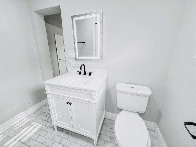 half bathroom featuring toilet, marble finish floor, baseboards, and vanity