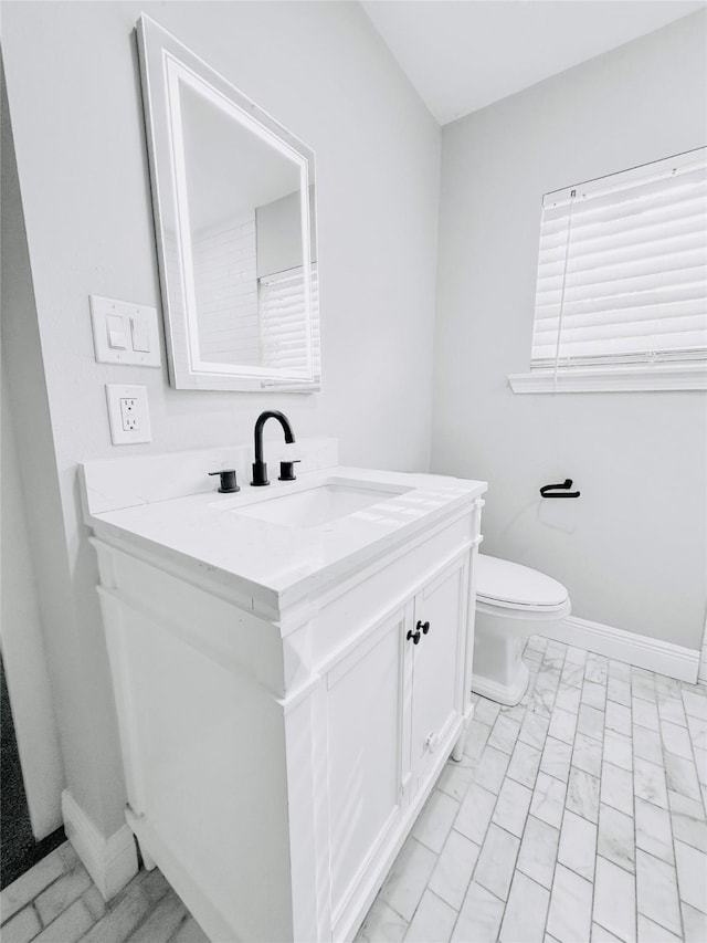 bathroom featuring toilet, vanity, and baseboards