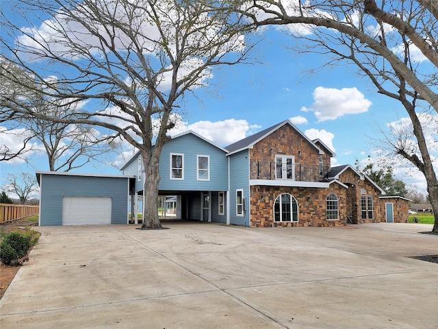 view of front of property with an outbuilding, a balcony, a garage, concrete driveway, and stone siding