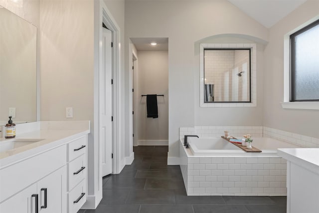 full bathroom with vanity, vaulted ceiling, a bath, and tile patterned flooring