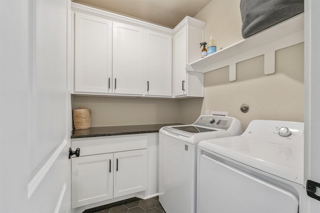 laundry area featuring washer and clothes dryer, cabinet space, and dark tile patterned flooring