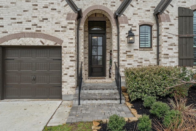 entrance to property featuring a garage and brick siding