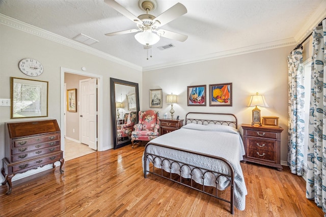 bedroom featuring light wood-style flooring, visible vents, a textured ceiling, and ornamental molding