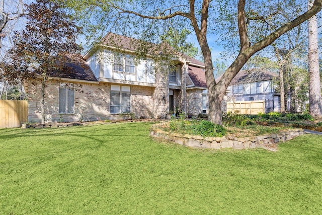 rear view of house with brick siding, fence, and a yard