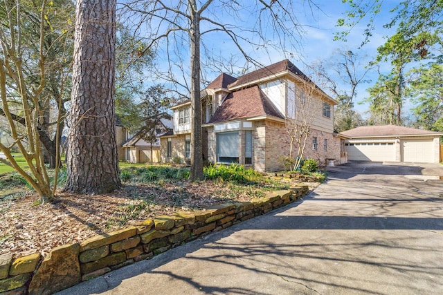 view of side of home with brick siding, a chimney, an outdoor structure, and a detached garage