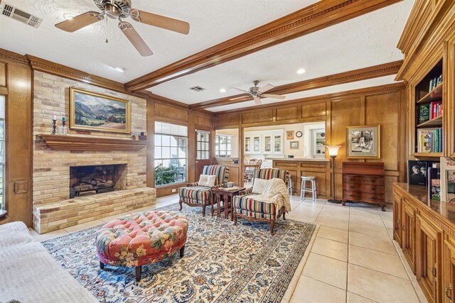 living area with beam ceiling, visible vents, a brick fireplace, light tile patterned flooring, and a textured ceiling