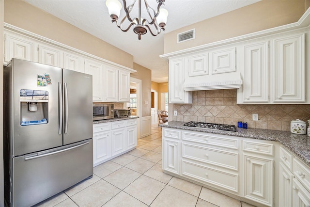 kitchen with light tile patterned floors, visible vents, light stone countertops, stainless steel appliances, and backsplash