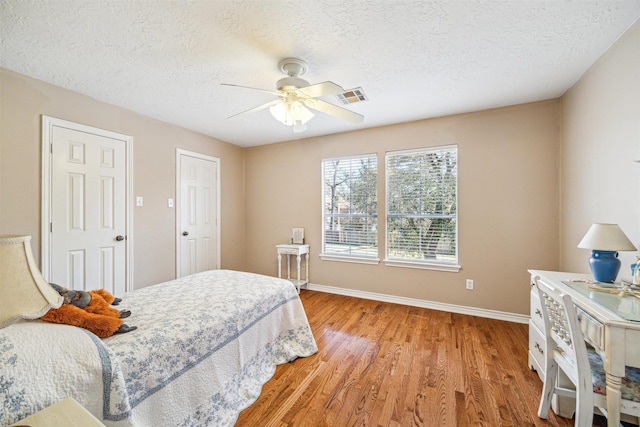 bedroom featuring a textured ceiling, light wood-type flooring, visible vents, and baseboards