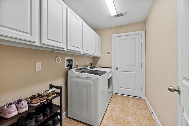 washroom with cabinet space, light tile patterned floors, baseboards, visible vents, and washer and clothes dryer