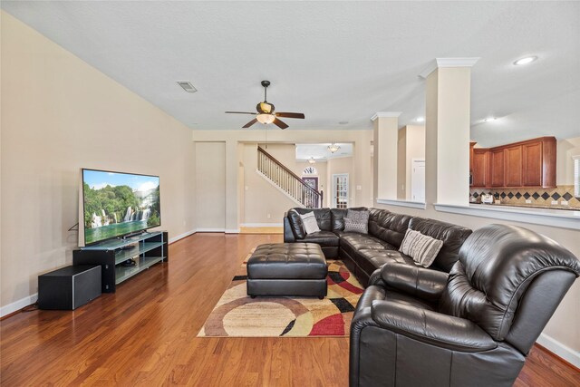 living room with stairs, wood finished floors, visible vents, and baseboards