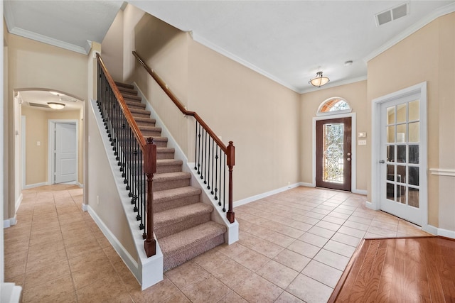 entrance foyer featuring arched walkways, ornamental molding, light tile patterned floors, and visible vents