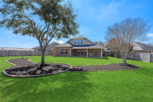 back of property featuring a yard, a fenced backyard, and brick siding