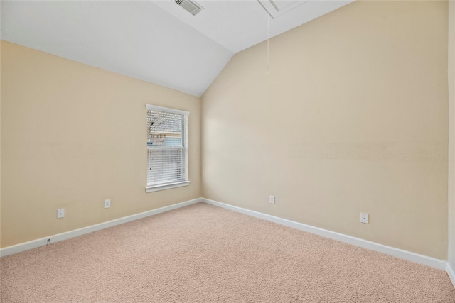 carpeted empty room with visible vents, vaulted ceiling, attic access, and baseboards