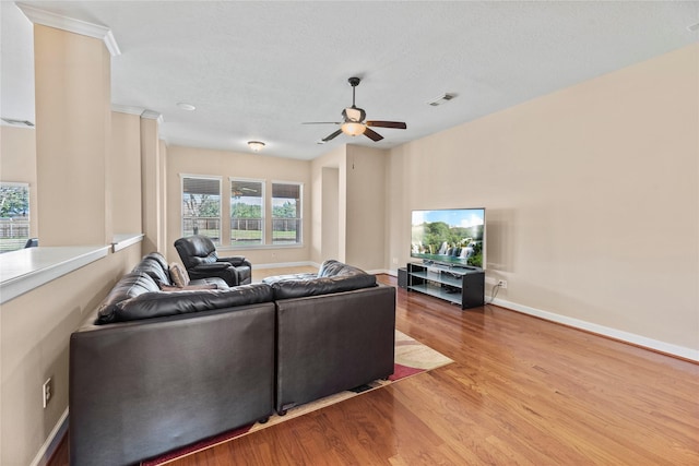 living area with a ceiling fan, wood finished floors, visible vents, and baseboards