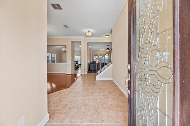 foyer entrance featuring visible vents, ornamental molding, tile patterned flooring, baseboards, and stairs