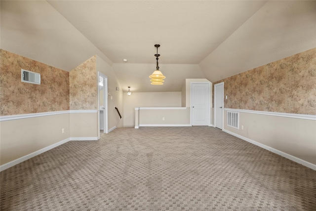 interior space with carpet floors, visible vents, vaulted ceiling, and baseboards