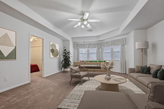 living area featuring carpet floors, ceiling fan, visible vents, and baseboards