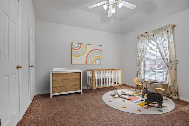 carpeted bedroom with ceiling fan, a crib, and baseboards