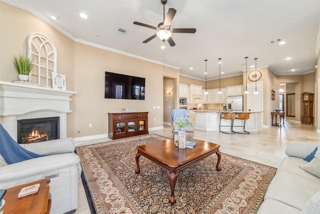 living room with a glass covered fireplace, visible vents, and crown molding