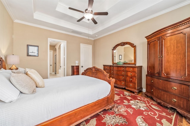 bedroom featuring wood finished floors, visible vents, a ceiling fan, a tray ceiling, and crown molding