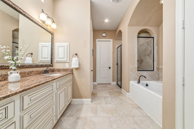 bathroom with a shower stall, baseboards, a bath, and vanity