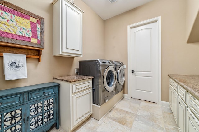 clothes washing area with independent washer and dryer, cabinet space, and baseboards