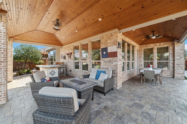 view of patio / terrace featuring outdoor dining space, fence, an outdoor kitchen, and an outdoor hangout area