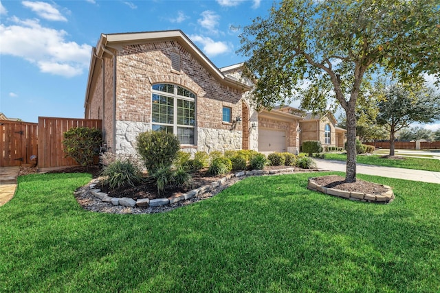 view of front of house featuring brick siding, concrete driveway, fence, a garage, and a front lawn