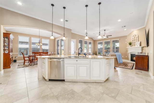 kitchen featuring light stone counters, a sink, open floor plan, stainless steel dishwasher, and a glass covered fireplace