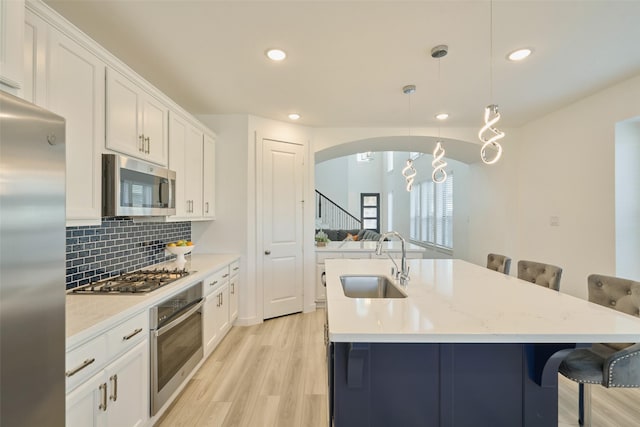 kitchen featuring tasteful backsplash, a breakfast bar area, stainless steel appliances, light wood-type flooring, and a sink