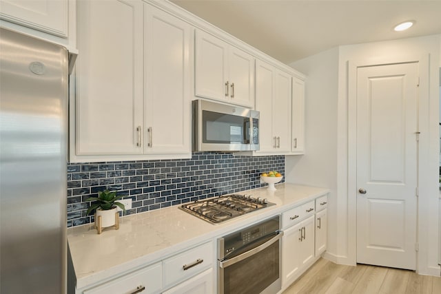 kitchen featuring light wood finished floors, appliances with stainless steel finishes, backsplash, and white cabinets