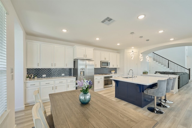 kitchen featuring arched walkways, a sink, visible vents, white cabinets, and appliances with stainless steel finishes