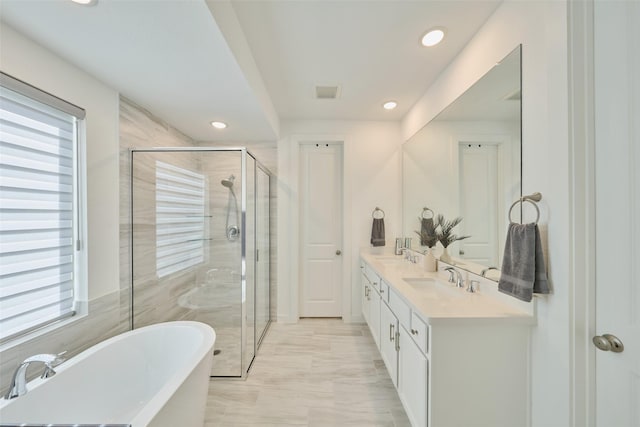 bathroom featuring a freestanding bath, a stall shower, and a sink