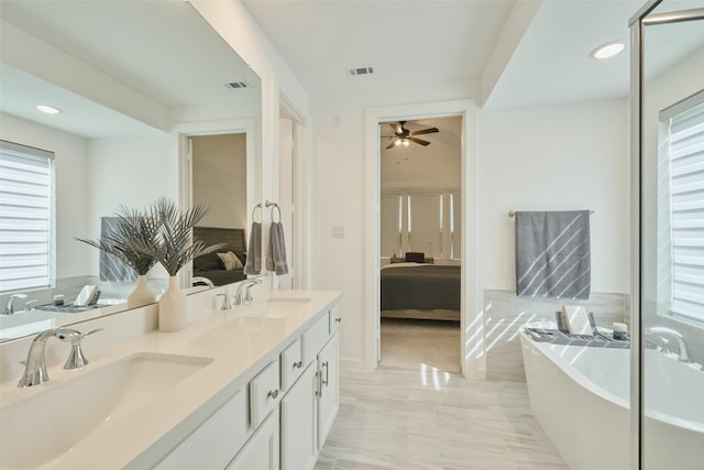 full bathroom featuring double vanity, a freestanding tub, visible vents, and a sink