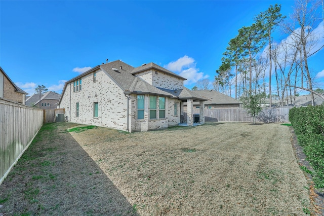 rear view of house with brick siding, a lawn, a fenced backyard, and central air condition unit