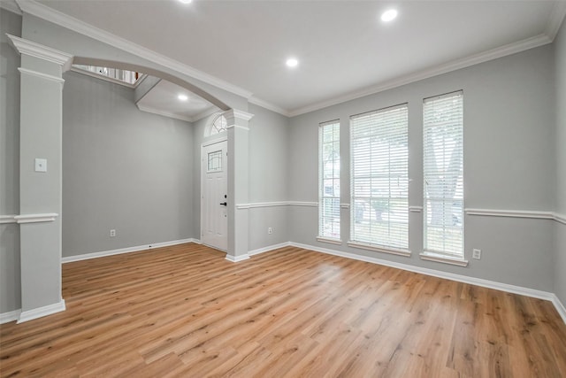 unfurnished room with arched walkways, wood finished floors, baseboards, ornamental molding, and decorative columns