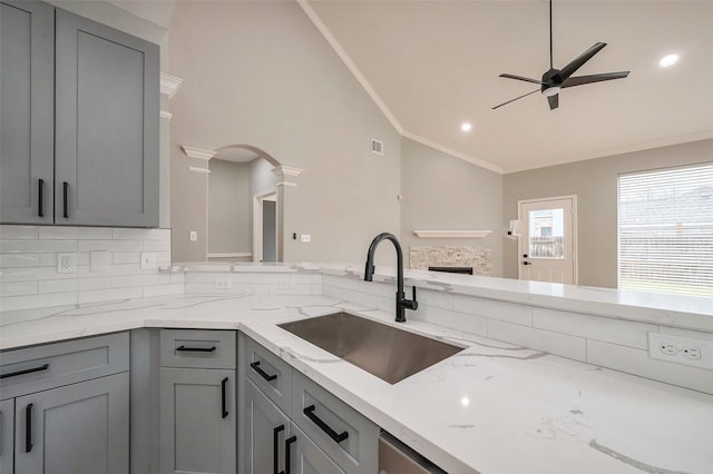 kitchen featuring crown molding, arched walkways, gray cabinets, and a sink