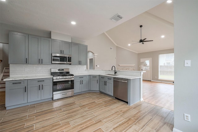 kitchen featuring gray cabinetry, a peninsula, a sink, visible vents, and appliances with stainless steel finishes