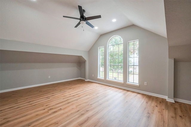 additional living space featuring vaulted ceiling, a ceiling fan, light wood-style flooring, and baseboards