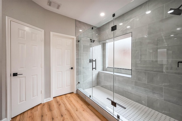 full bath with a stall shower, visible vents, and wood finished floors