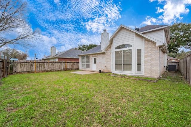 back of property with brick siding, a yard, a chimney, a patio, and a fenced backyard